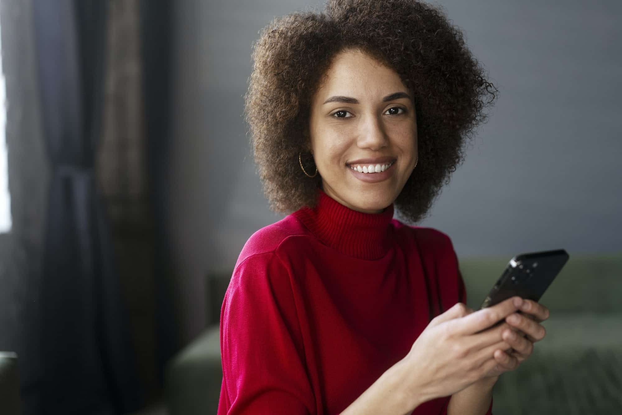 african american woman in red casual attire using mobile phone working online text messaging